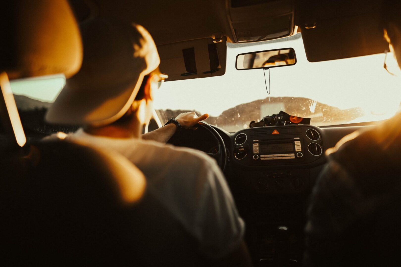 A man driving in the sun while wearing a hat.